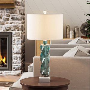 A luxurious and gorgeous Urban Ambiance UEX7110 Contemporary Table Lamp in Clear Seeded Blue finish enhances the ambiance of a living room with a fireplace.