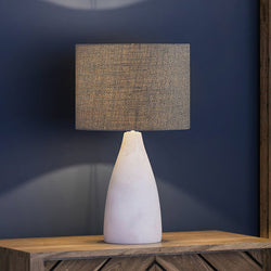 A beautiful organic table lamp with a grey shade on top of a dresser.