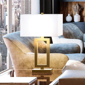 A living room with a unique Urban Ambiance UEX7260 Contemporary Table Lamp 15''W x 8''D x 26''H, Antique Brass Finish, Bisbee Collection