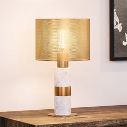 A beautiful and unique UEX7280 Glam Table Lamp with a White and Aged Brass Finish from the Frenchtown Collection by Urban Ambiance on a wooden table.
