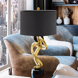 A black and gold UEX7300 Glam Table Lamp 15''W x 15''D x 30''H, Gold and Black Finish, Astoria Collection in a living room by Urban
