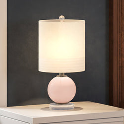 A beautiful UEX7410 Retro Table Lamp with a clear pink and white finish from the Lanesboro Collection by Urban Ambiance provides gorgeous lighting on top of a white dresser.