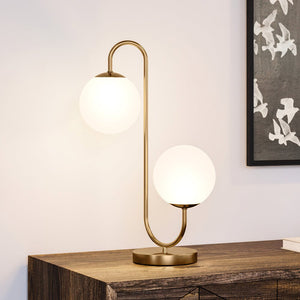 A unique and luxurious UEX7582 Mid-Century-Modern Table Lamp with two glass globes on it, featuring an aged brass finish from the Sewanee Collection by Urban Ambiance.