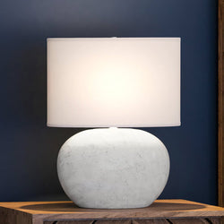 A unique lighting fixture, the UEX7610 Coastal Table Lamp from the Stowe Collection by Urban Ambiance with a gorgeous white finish, sits atop a wooden table.