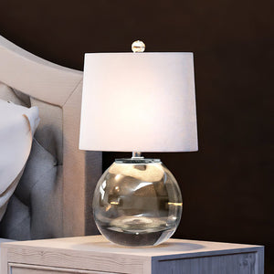 A beautiful Coastal Table Lamp 12''W x 8''D x 19''H, Clear Finish, McCall Collection by Urban Ambiance on a bedside table.