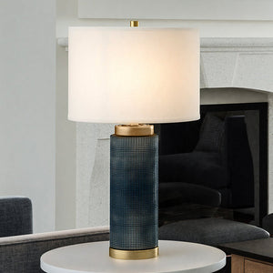 A gorgeous table lamp with a Dark Blue and Antique Brass Finish from the Big Sky Collection, providing stunning lighting in a living room.