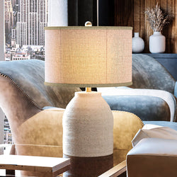 A unique coastal table lamp in an earth gray finish, providing gorgeous lighting in a living room with a city view.