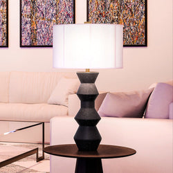 A unique UEX7940 Modern Table Lamp with a gorgeous, dark navy blue glazed finish from the Ann Arbor Collection by Urban Ambiance on a table in a living room.