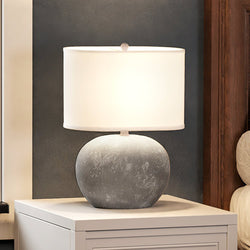 A unique and beautiful bedside table with a UEX8050 Organic Table Lamp 16''W x 9''D x 20''H, Concrete Finish, Conroe Collection on it