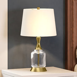 A beautiful and luxurious UEX8170 Glam Table Lamp with a glass shade on top of a bed.