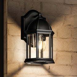An UHP1375 Tudor Outdoor Wall Sconce lighting fixture from the Greensboro Collection by Urban Ambiance on a brick wall.
