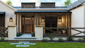 A modern farmhouse features white brick, wood porch, double doors with clear glass, dormer windows, and Urban Ambiance's UHP1381 Farmhouse Outdoor Wall Sconce in Olde Bronze from the Macon Collection on its marine-grade exterior.
