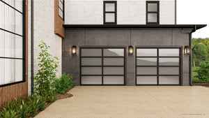 Modern house exterior with two frosted glass garage doors, concrete driveway, white brick and dark gray walls, landscaped plants, and a stylish UHP1382 Farmhouse Outdoor Wall Sconce by Urban Ambiance in Olde Bronze for outdoor illumination.