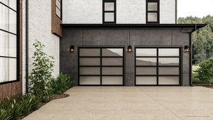 Modern house exterior with two black-framed glass garage doors, white brick walls, landscaped driveway plants, and Urban Ambiance's UHP1385 Farmhouse Outdoor Wall Sconce (11.875''H x 5.5''W), midnight black finish, marine-grade from the Macon Collection.