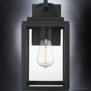 The Urban Ambiance UHP1386 Macon Collection outdoor wall sconce features marine-grade construction, a midnight black finish, clear glass sides, and an exposed bulb for modern farmhouse style. Size: 13.625''H x 7.125''W.