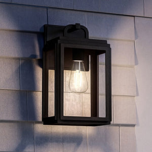 The Urban Ambiance UHP1386 Farmhouse Outdoor Wall Sconce from the Macon Collection features a corrosion-resistant marine-grade midnight black finish and clear glass, illuminating modern exteriors in style against gray siding.