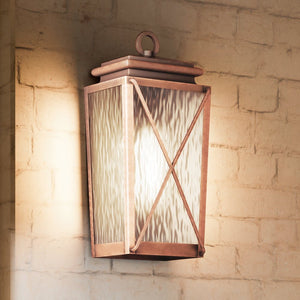 A beautiful Urban Ambiance UHP1411 Vintage Outdoor Wall Sconce lamp, with an Antique Copper Finish, in the Buffalo Collection, on a brick wall.