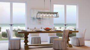 A unique dining room with an Urban Ambiance UHP3913 Industrial Chandelier, providing a stunning lighting fixture above a Berkeley Collection table and chairs, and a view of the ocean.