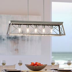 A unique lighting fixture, the Urban Ambiance UHP3913 Industrial Chandelier 9''H x 38''W with Galvanized Steel Finish from Berkeley Collection hangs over a dining table.