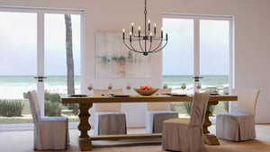 A dining room with a unique lighting fixture, the UHP3975 Modern Farmhouse Chandelier, and a view of the ocean.