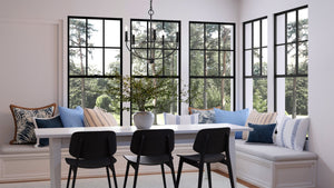 An Urban Ambiance UHP3976 Modern Farmhouse Chandelier, a luxury lighting fixture with a Midnight Black Finish, in a dining room with large windows and chairs.