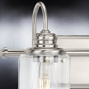 A unique vintage bath light fixture from the Hedland Collection featuring a brushed nickel finish and clear glass jar, adding a touch of luxury to any urban ambiance.