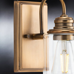 A unique UHP4065 Vintage Wall Sconce 9.875''H x 4.5''W, Olde Brass Finish, Hedland Collection with a clear glass bulb