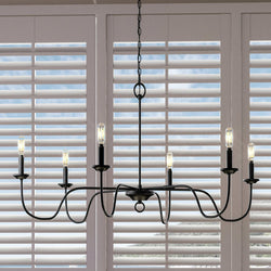 A gorgeous Urban Ambiance UHP4081 Traditional Chandelier 24''H x 40''W, Midnight Black Finish, Warwick Collection in front of a window with shutters.