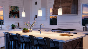 A kitchen with a large island and bar stools featuring the unique UHP4103 Modern Pendant 11''H x 5''W, Brushed Nickel Finish from the Broome Collection by Urban Amb
