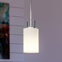 An UHP4103 Modern Pendant 11''H x 5''W, Brushed Nickel Finish, Broome Collection lighting fixture hanging in a room with a painting on the wall.