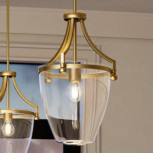 Two gorgeous pendant lighting fixtures from the unique Coronado Collection, with a brushed bronze finish, hanging in a room with a window.