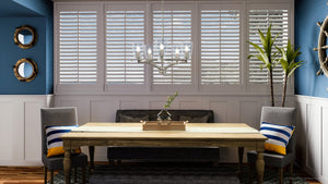 A dining room with blue walls and wooden shutters is complimented with the luxurious UHP4262 Traditional Chandelier 12.5''H x 25.25''W in Brush