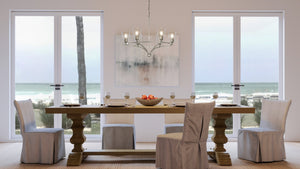 An Urban Ambiance UHP4263 Traditional Chandelier 14''H x 30''W, a unique lighting fixture in the Coronado Collection dining room with a view of the ocean.