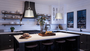 A luxury kitchen with white cabinets and black countertops, featuring the UHP4264 New Traditional Pendant 11.875''H x 12.375''W lighting fixture from the Coronado Collection by
