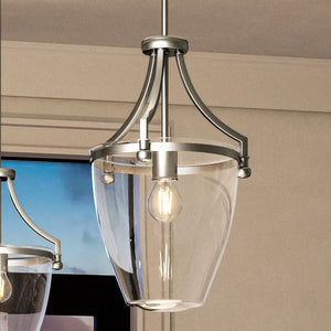 A beautiful light fixture from the Coronado Collection, the Urban Ambiance UHP4266 Traditional Pendant exudes luxury with its brushed nickel finish and glass shade hanging elegantly over a window.