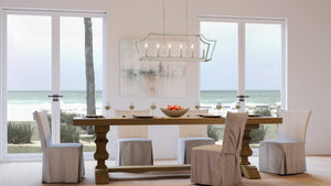 A dining room with a unique UHP4271 Traditional Chandelier, featuring a luxurious brushed nickel finish and an expansive view of the ocean.