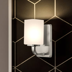 A Unique Urban Ambiance UHP4320 Contemporary Wall Sconce with a glass shade on a black and white tiled wall.