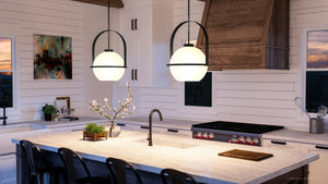 A kitchen with a large island and two luxury pendant lights.