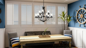 A dining room with blue walls and white shutters, featuring the beautiful UHP4371 Contemporary Chandelier 29''H x 32''W, Midnight Black Finish, Mesa Collection from Urban Amb