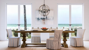 A dining room with a beautiful view of the ocean, adorned with a unique Urban Ambiance UHP4404 Farmhouse Chandelier.