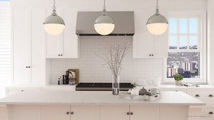 A kitchen with white cabinets and a large island featuring a gorgeous lighting fixture, the ULB2001 Modern Farmhouse Pendant from the Apulon Collection by Urban Ambiance.