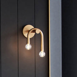 A unique ULB2212 Mid-Century Modern Wall Sconce from the Kenmare Collection by Urban Ambiance on a black wall.