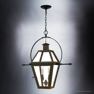 Introducing the Urban Ambiance UQL1378 Historic Outdoor Pendant Light from the Paris Collection, featuring a striking 23.5-inch tall by 21.25-inch wide circular frame in a Bygone Bronze finish. This metal and glass pendant evokes the timeless elegance of a handcrafted colonial gas lantern, with its chain suspension and two candle-style bulbs visible inside. Perfect as an outdoor accent, it infuses any space with classic charm and refined illumination.
