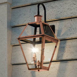The Urban Ambiance UQL1382 Historic Outdoor Wall Light from the Paris Collection showcases a handcrafted vintage outdoor lighting style, with a rustic copper finish, clear glass enclosure, and dual light bulbs. Measuring 22.5″ high by 10.5″ wide, it is displayed mounted on a textured concrete wall with horizontal grooves.