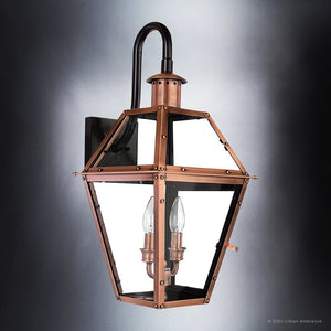 The Urban Ambiance UQL1382 Historic Outdoor Wall Light from the Paris Collection features a rustic copper finish, glass panels, and a black mounting plate. Measuring 22.5″H x 10.5″W, this vintage-inspired sconce accommodates two candle-style bulbs and is photographed against a gradient gray background.