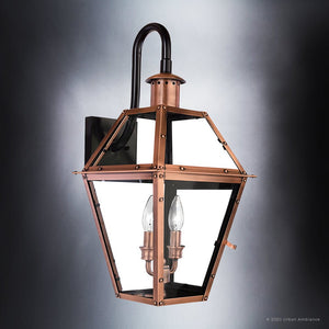 Elevate your outdoor space with the UQL1382 Historic Outdoor Wall Light from Urban Ambiance’s Paris Collection, featuring a handcrafted rustic copper finish, a hexagonal glass enclosure, and two candle-style bulbs mounted on a black metal backplate—an elegant 22.5″ high by 10.5″ wide fixture that brings classic charm and timeless vintage style to any setting.