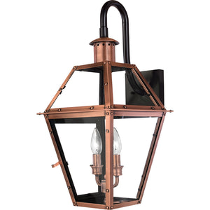 The Urban Ambiance UQL1382 Historic Outdoor Wall Light from the Paris Collection features a rustic copper finish, clear glass panels, and two candle-style light bulbs mounted on a black backplate with a curved arm; at 22.5″ high by 10.5″ wide, this sconce brings timeless charm and vintage elegance to your exterior spaces.