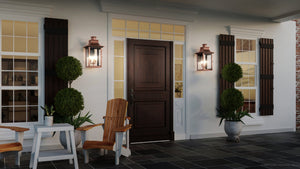 Front porch featuring a dark wooden door, Urban Ambiance UQL1411 Vintage Outdoor Wall Light from the Longview Collection with a rustic copper finish (23″H x 12″W), potted plants, Adirondack chairs, side table, and windows with shutters on a tiled floor.