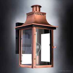 The Urban Ambiance UQL1413 Vintage Outdoor Wall Light from the Longview Collection features a rustic copper finish, clear glass panels with a visible bulb, and a rectangular mounting plate—evoking the timeless charm of classic gaslight lanterns. Measures 15.3″ high by 7.75″ wide and is shown against a gray background.