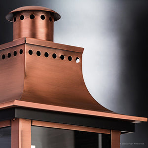 A close-up of the Urban Ambiance UQL1413 Vintage Outdoor Wall Light from the Longview Collection, featuring a rustic copper finish and a vented top inspired by classic gaslight lanterns, set against a gradient black and white background.